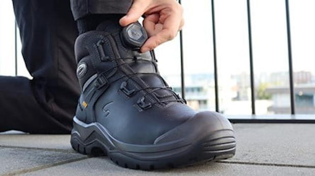 Close-up van een vakman die BOA werkschoenen vastdraait op een bouwplaats