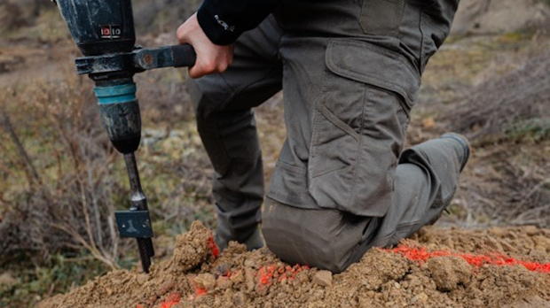 Vakman werkt op de knieën in de grond met ergonomische kniebeschermers