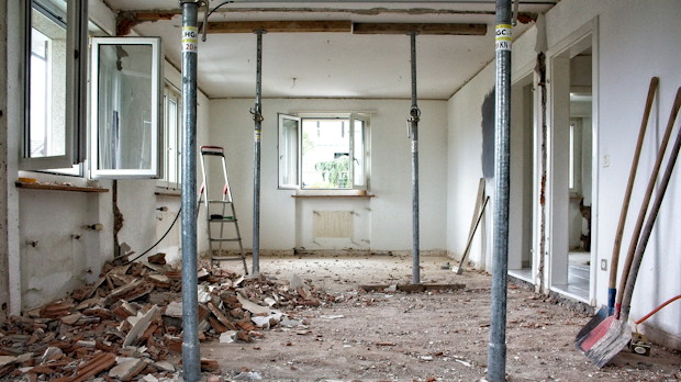 Woning in verbouwing met gestut plafond en bouwpuin op de vloer, illustratie van 55-plussers die verbouwen en verduurzamen