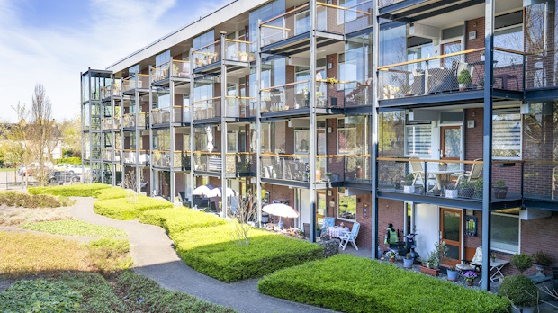 Three-story brick apartment building with metal balconies surrounding a curved green courtyard.] but we should fix to only one line without stray bracket. Let's correct.