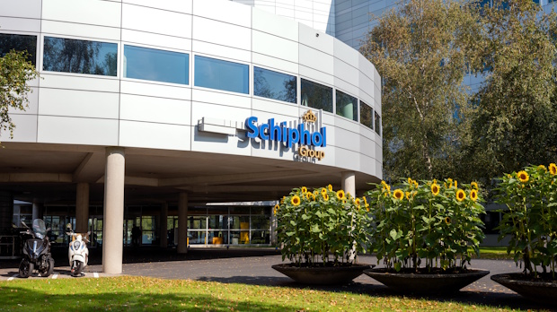 Front view of the Schiphol Group building with a curved white façade and sunflowers in planters at the entrance.